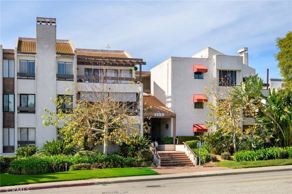 Front view of a multi-story building with balconies and red awnings.