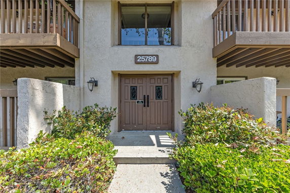 Front view of a building entrance with a brown double door and balconies.