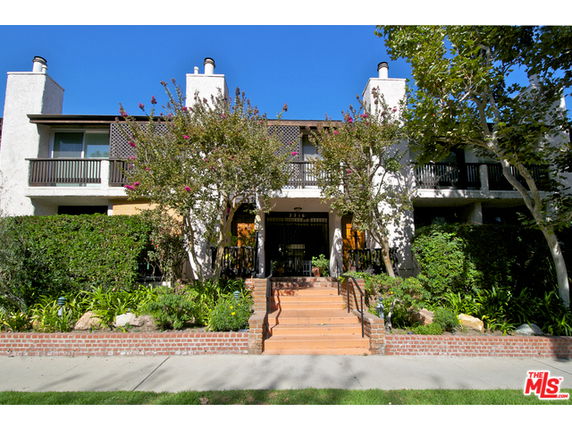 Front view of a two-story building with balconies and a landscaped entrance.