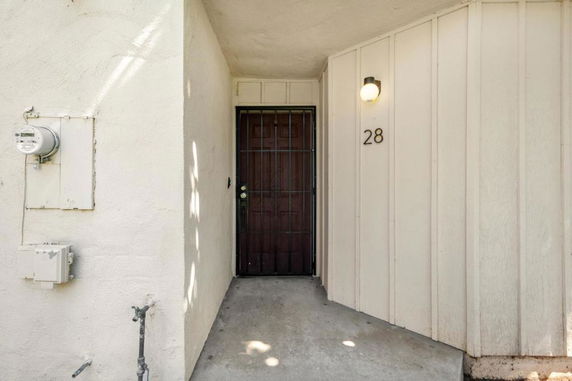 Front view of a house entrance with a wooden door and wall-mounted light.