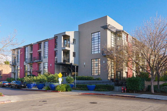 Front view of a modern multi-story apartment building with large windows and balconies.