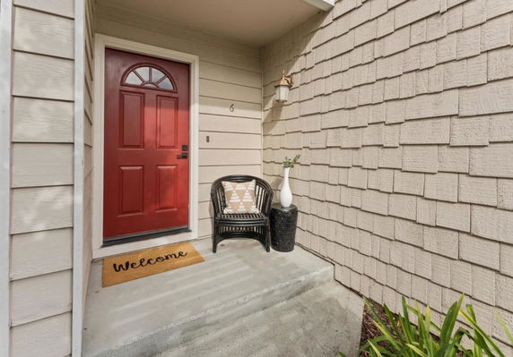 Front view of a house entrance with a red door and a welcome mat.