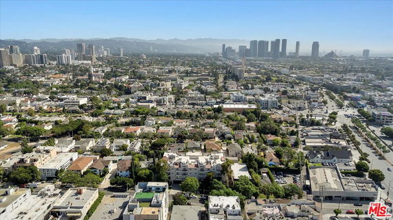 A wide-angle view of an urban area with numerous buildings, roads, and distant skyscrapers under a clear blue sky.