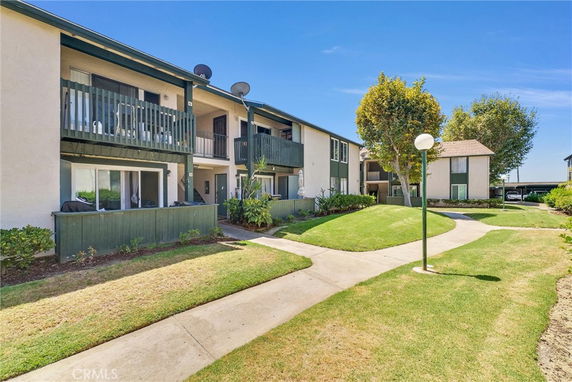 Front view of a two-story apartment building with balconies and green area.