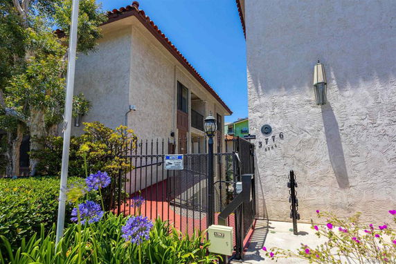 Front view of a two-story building with a gated entrance and stucco exterior.