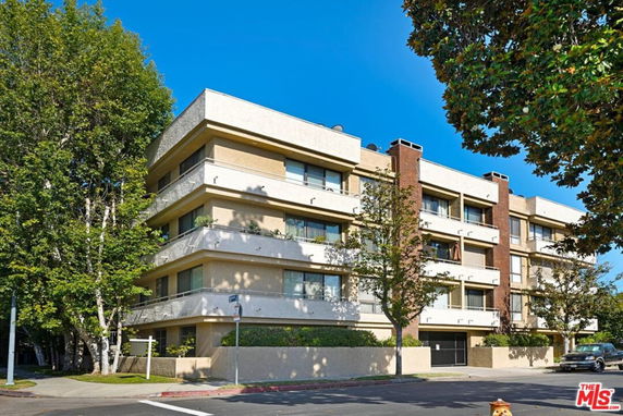 Front view of a multi-story residential building with balconies and striped awnings.