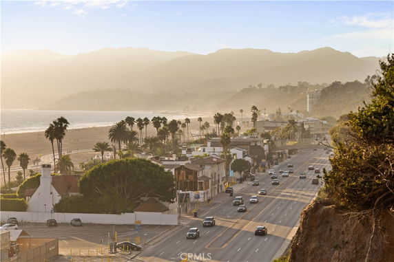 Panoramic view of a coastal highway and beachfront area with surrounding mountains.