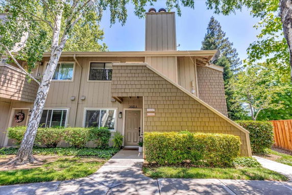 Front view of a two-story house with a unique roof design and beige siding.