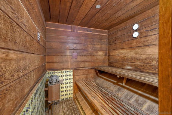Interior view of a wooden sauna room with benches and a heater.