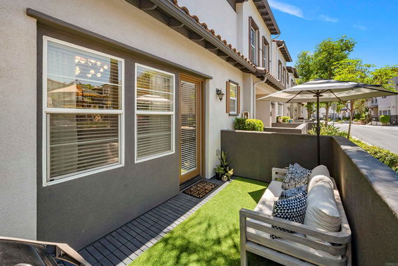 Front view of a townhouse with a small patio seating area.