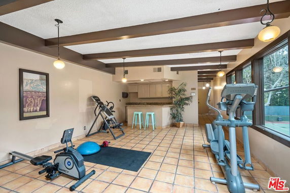 Indoor gym area with exercise equipment in a room with tiled floor and overhead lighting.