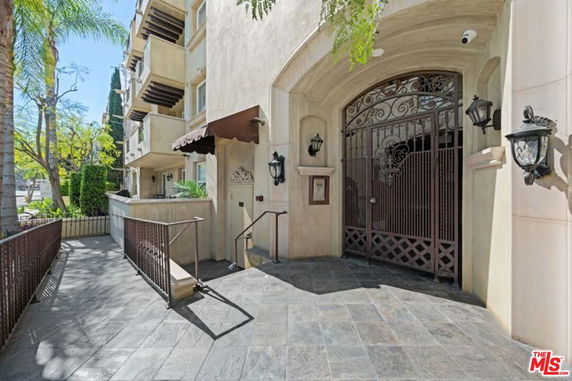 Front entrance of a multi-story building with ornate gate and balconies.