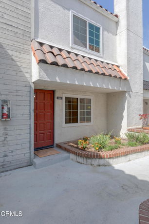 Front view of a two-story house with a red door and roof tiles.