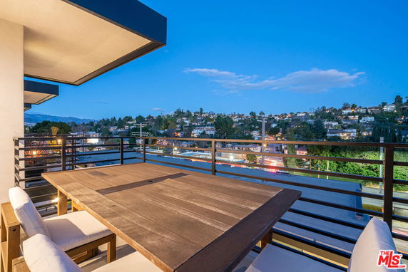 Outdoor viewing area with table and chairs overlooking a residential area at dusk.