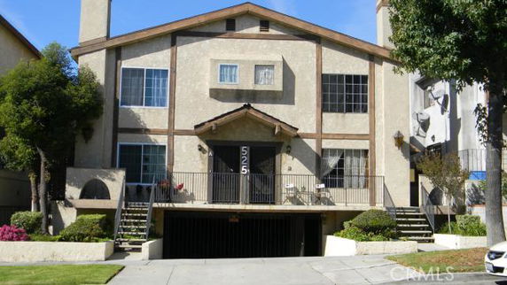 Front view of a multi-story residential building with an entrance staircase and garage.