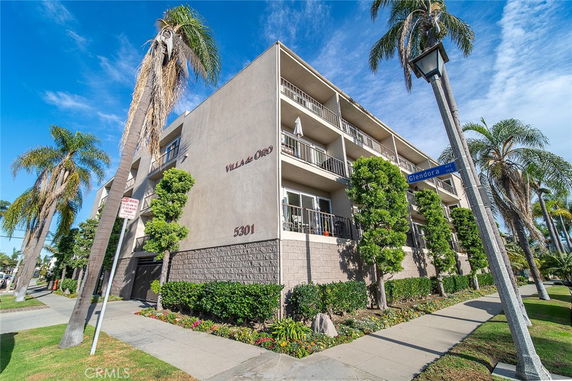 Front view of a multi-story apartment building with balconies and a sign indicating 'Villa de Oro'.