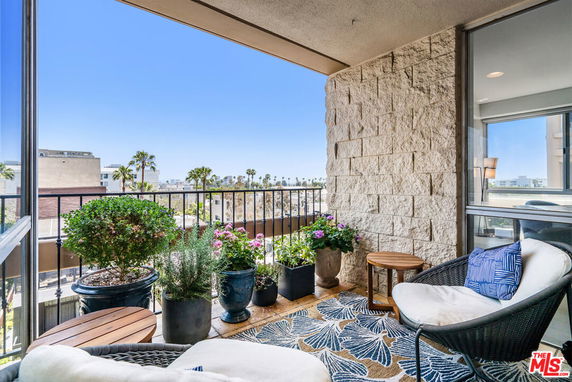 Balcony with seating and plants overlooking cityscape.