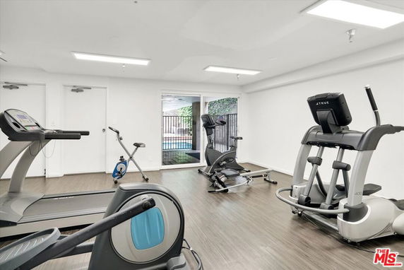 Room with exercise equipment including treadmill and elliptical machines.