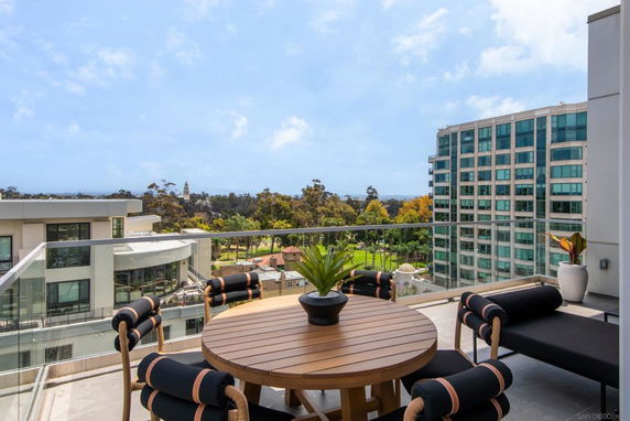 View from a balcony overlooking buildings and a park with trees in the distance.