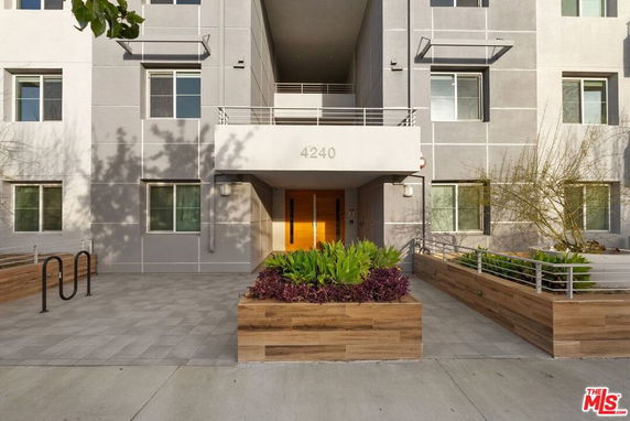 Front view of a modern multi-story building with large windows and planter boxes.