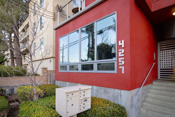Front view of a modern red multi-story building with large windows.