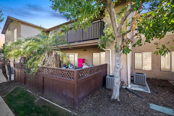 Front view of a two-story house with a balcony and fenced area.