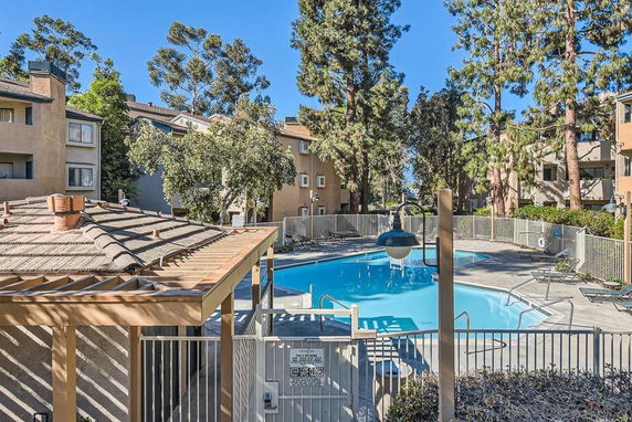 Outdoor swimming pool surrounded by trees and residential buildings.