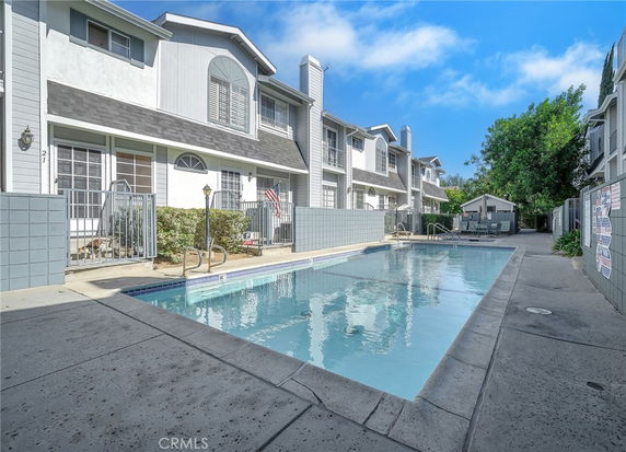 Outdoor swimming pool adjacent to a row of two-story houses.