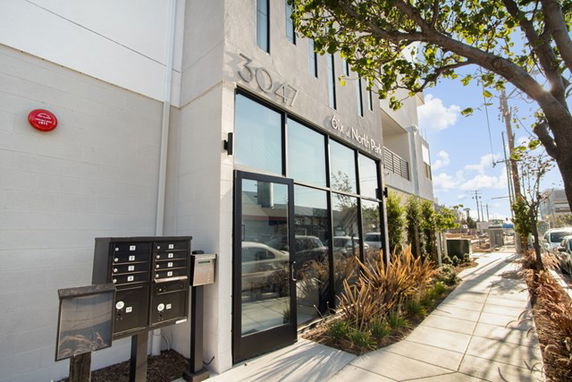 Front view of a modern multi-story building with large glass doors and address numbers displayed.