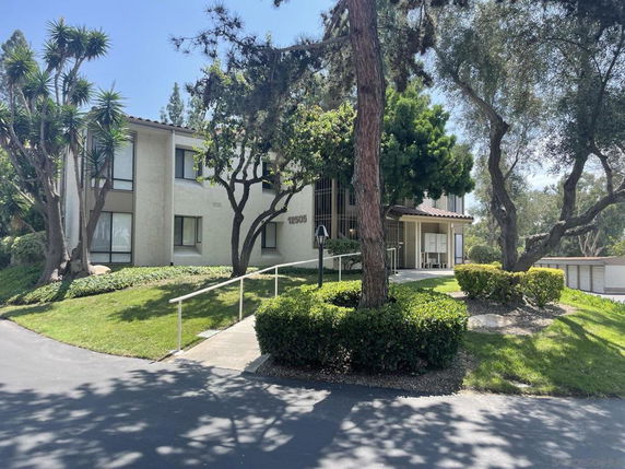 Front view of a two-story residential building surrounded by trees.
