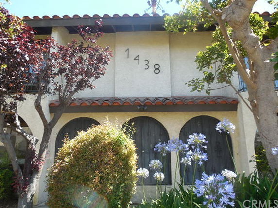 Front view of a two-story building with arched doorways and a tiled roof.