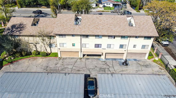 Aerial view of a two-story apartment building with a beige facade and multiple garage doors.