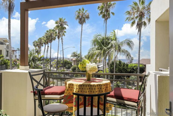 View from a balcony overlooking palm trees and buildings.