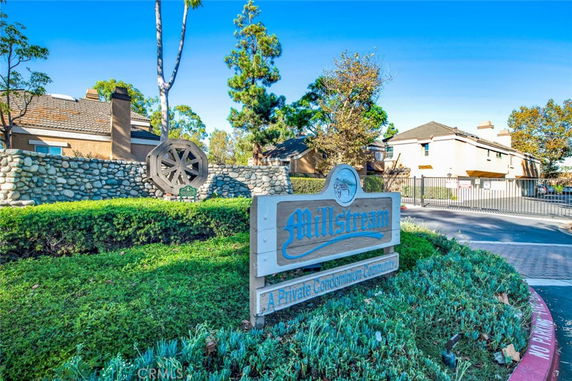 Front view of a gated condominium community with stone wall and sign.