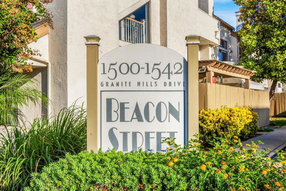 Front view of a multi-story building with a name sign in front.