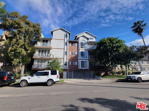 Front view of a multi-story residential building with balconies and a mix of brick and siding exterior.