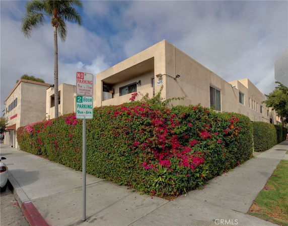 Front view of a two-story building with beige exterior and hedges.