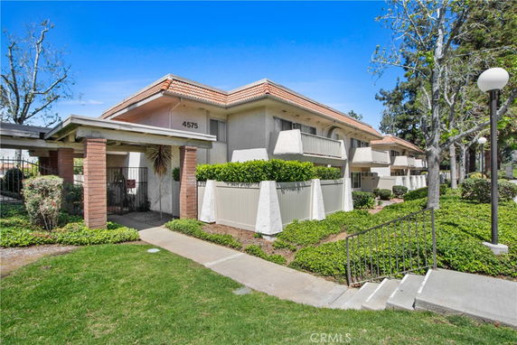 Front view of a multi-story residential building with balconies and a tiled roof.