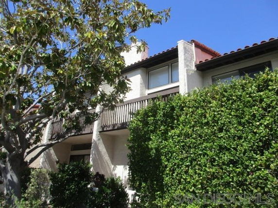 Front view of a multi-story house with a balcony and a sloped roof.