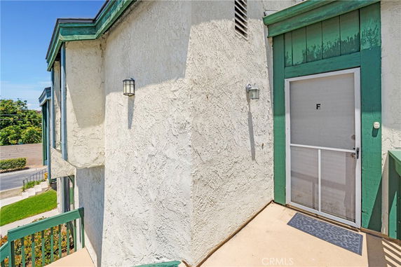 Outdoor entrance view of an apartment with a green-framed door marked 'F'.