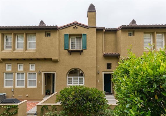 Front view of a two-story townhouse with arched windows and green shutters.