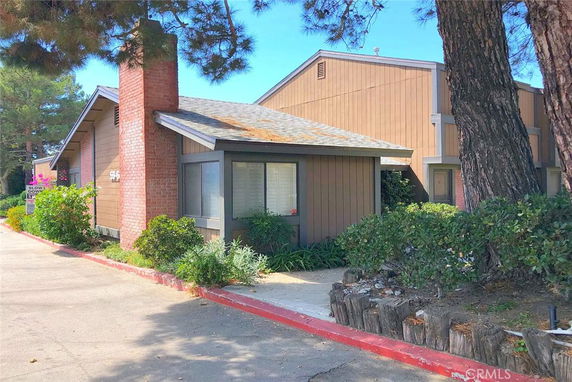 Front view of a house with a brick chimney and wood siding.