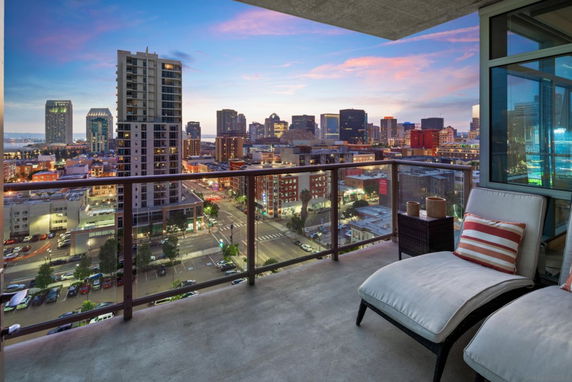 Panoramic view from a building balcony overlooking a cityscape with high-rise buildings at dusk.