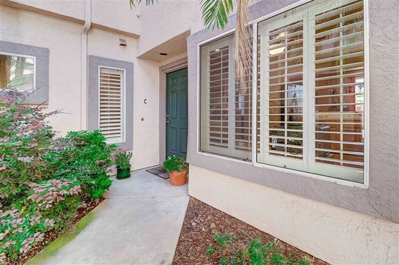 Front view of a house with a green front door and large windows with shutters.