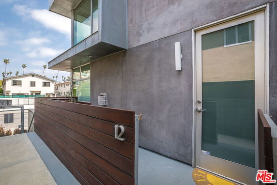 Exterior view of a modern building entrance with a glass door and wooden paneling.
