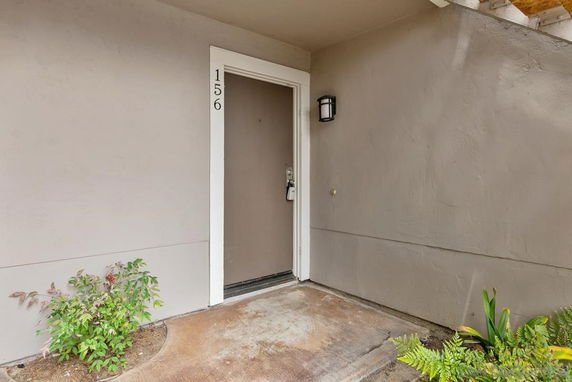 Entrance view of a house with a brown door and wall light.