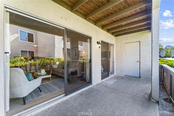 Exterior view showing a patio area with sliding glass doors leading into a living room.