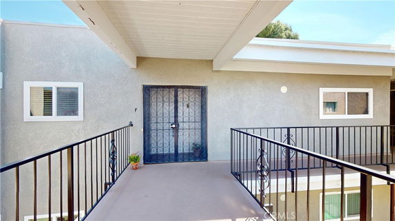 Front view of a building entrance with metal railing and a door with security bars.