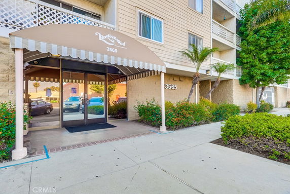 Entrance view of a multi-story building with an awning and glass doors.