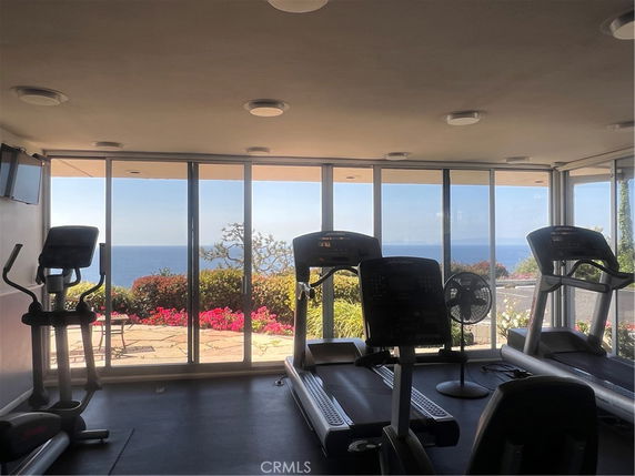 Indoor gym area with treadmills and exercise equipment, featuring large glass windows.